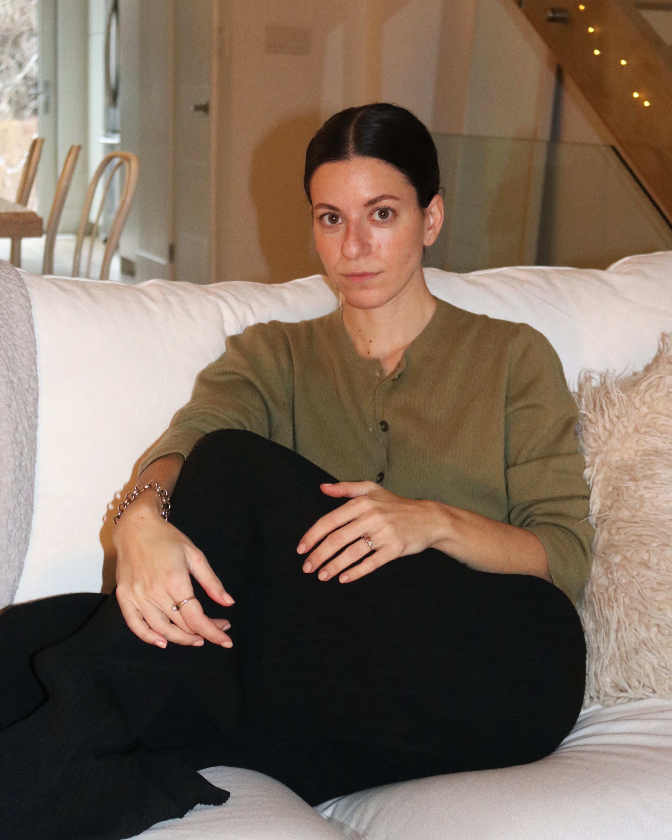 Woman sitting on couch, neutral makeup, glossy cheeks