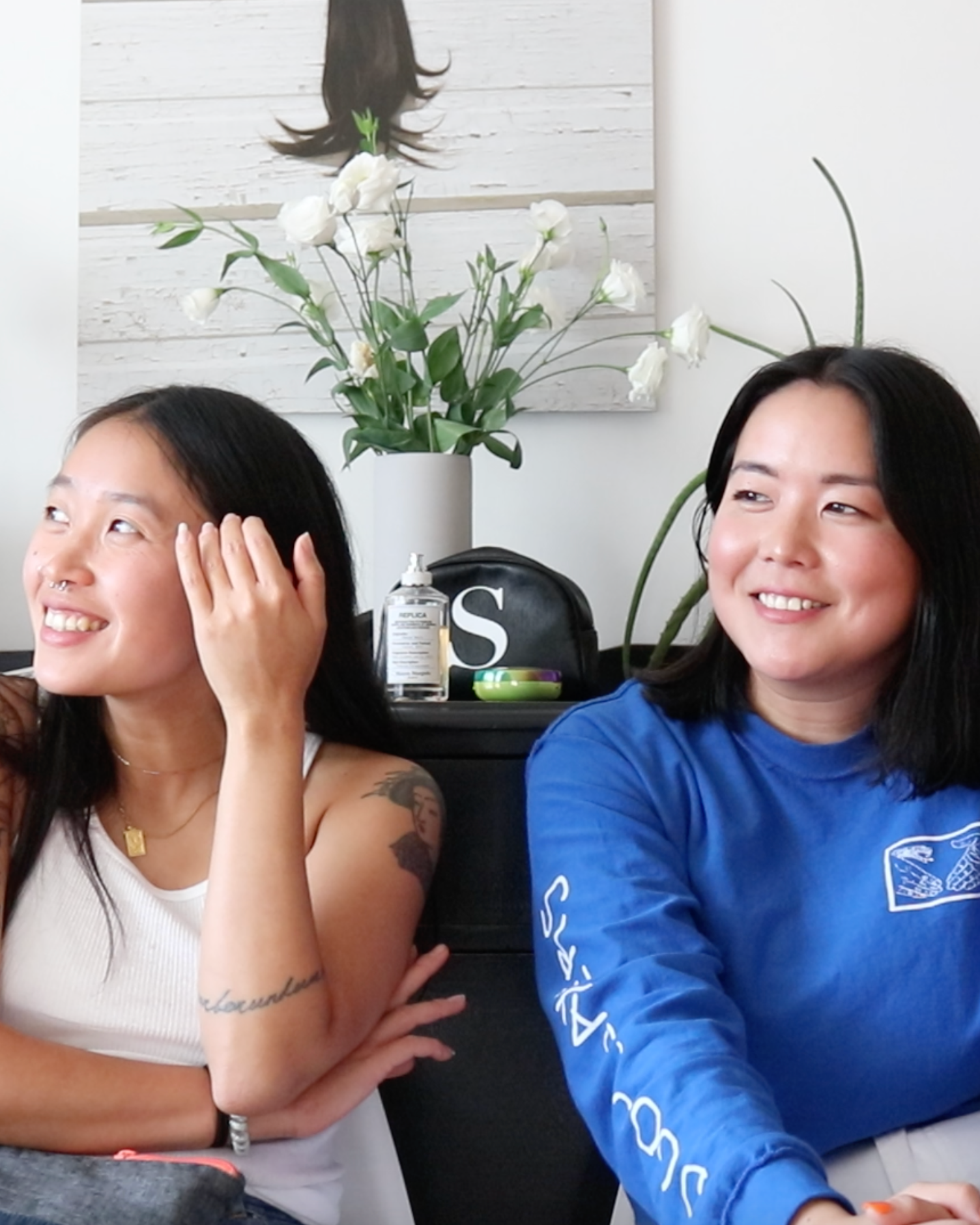 Two friends sitting, smiling, glossy lips and cheeks, makeup